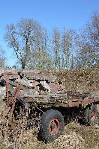 Een oude wagen naast een stapel stenen